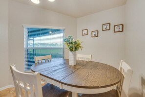 Une salle à manger avec une table ronde, des chaises blanches, une plante en pot et des tableaux encadrés accrochés au mur.