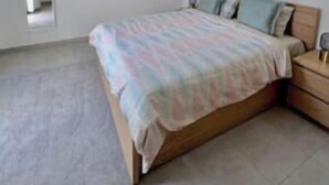 Quarto com cama, mesas de cabeceira e luminária no teto.