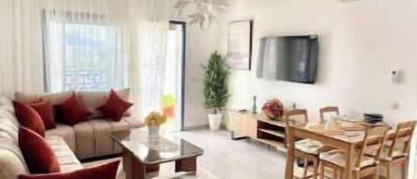A modern living room with a sofa, coffee table, and dining area.