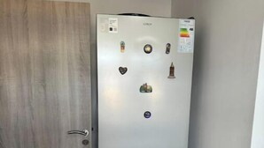 Uma geladeira compacta de duas portas, com freezer na parte superior e refrigerador abaixo, apresentando um painel de controle com vários botões e uma tela digital.