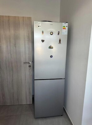 Ein kompakter, zweiteiliger Kühlschrank mit Gefrierfach oben und Kühlbereich darunter, mit einer Bedienkonsole mit verschiedenen Tasten und einem digitalen Display.