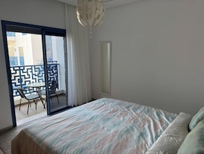 A hotel room with a bed, a balcony with a patterned railing, and a chandelier. - Ideal apartment for families (Martil)
