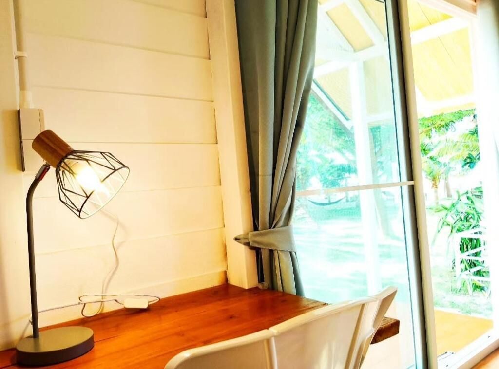 A room with a desk, a chair, a lamp, and a window with curtains.