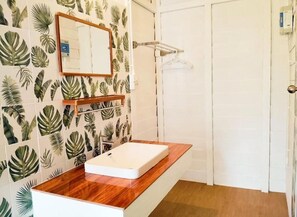 Un baño con tocador de madera, un lavamanos blanco y un espejo.