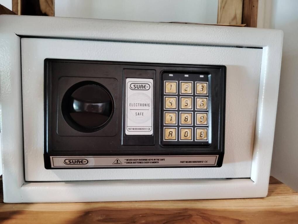Um cofre eletrônico branco com teclado e mecanismo de fechadura circular.