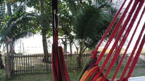 A hammock suspended between trees in a grassy area with a wooden fence in the background. - koh phaluai beach cottage (Chang Wat Surat Thani)