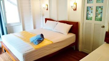 Ein Einzelbett mit Holzrahmen, weißer Bettwäsche und einem aufgelaminierten Handtuch auf einer gelben Matte.