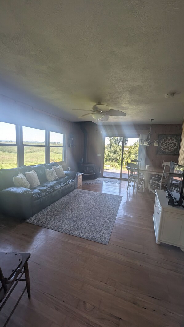 A spacious living room with a large sofa, a fireplace, and a view of the outdoors.