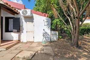 A residential property with a white exterior, a red roof, a window with a shutter, and a door. - Casa Sosi - Costa Rei: Charming Holiday Home Near Beach with Garden and Sea View (Costa Rei)