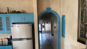 Een keuken met een koelkast van roestvrij staal, blauwe kastjes en een houten vloer.