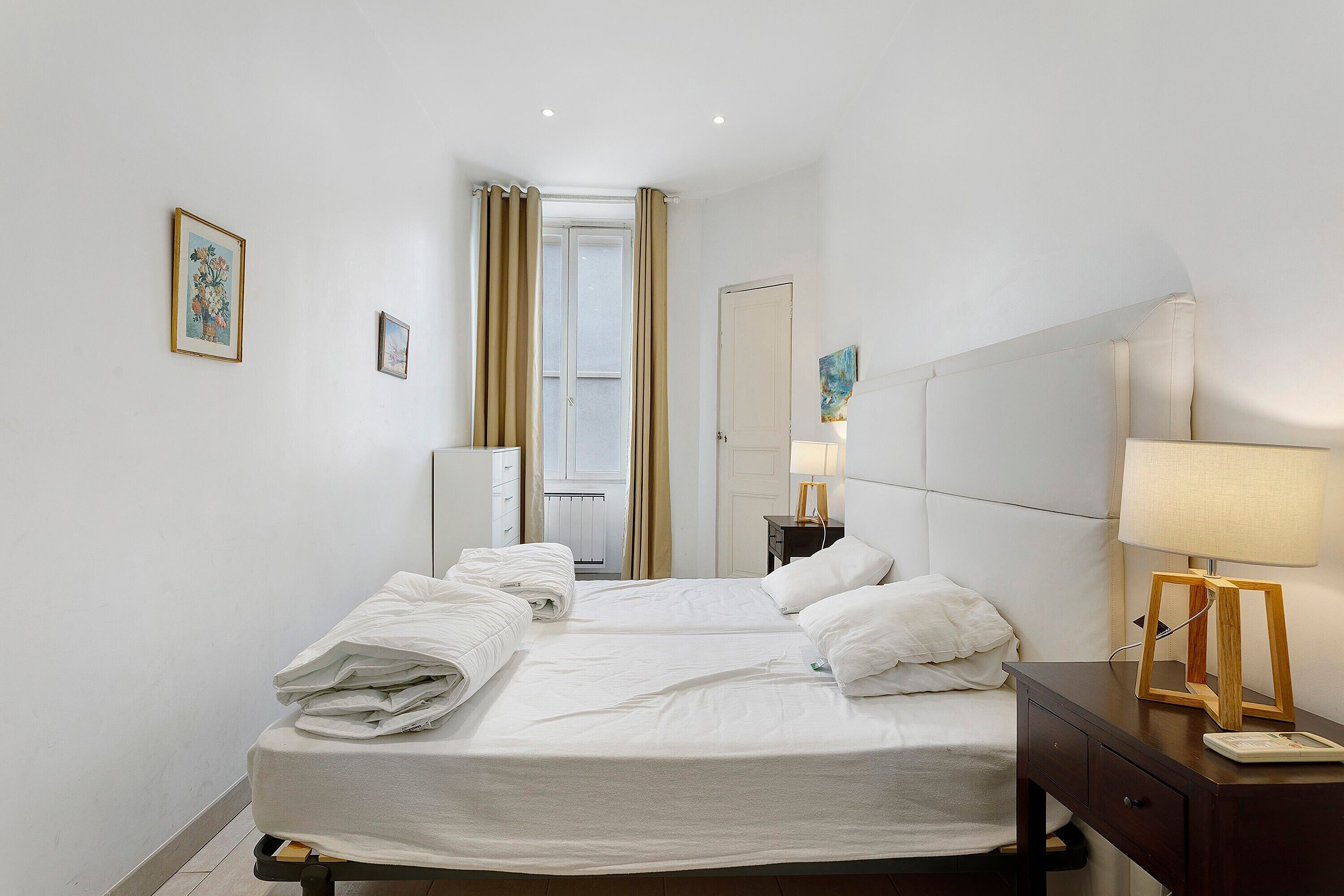 Een hotelkamer met een bed, een nachtkastje met een lamp, een dressoir en een spiegel.