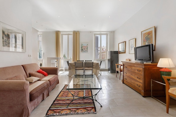 A modern living room with a sofa, a coffee table, a TV, and a dining area with chairs and a table. - Apartment '2 Bedroom  Cannes Center' (Cannes)