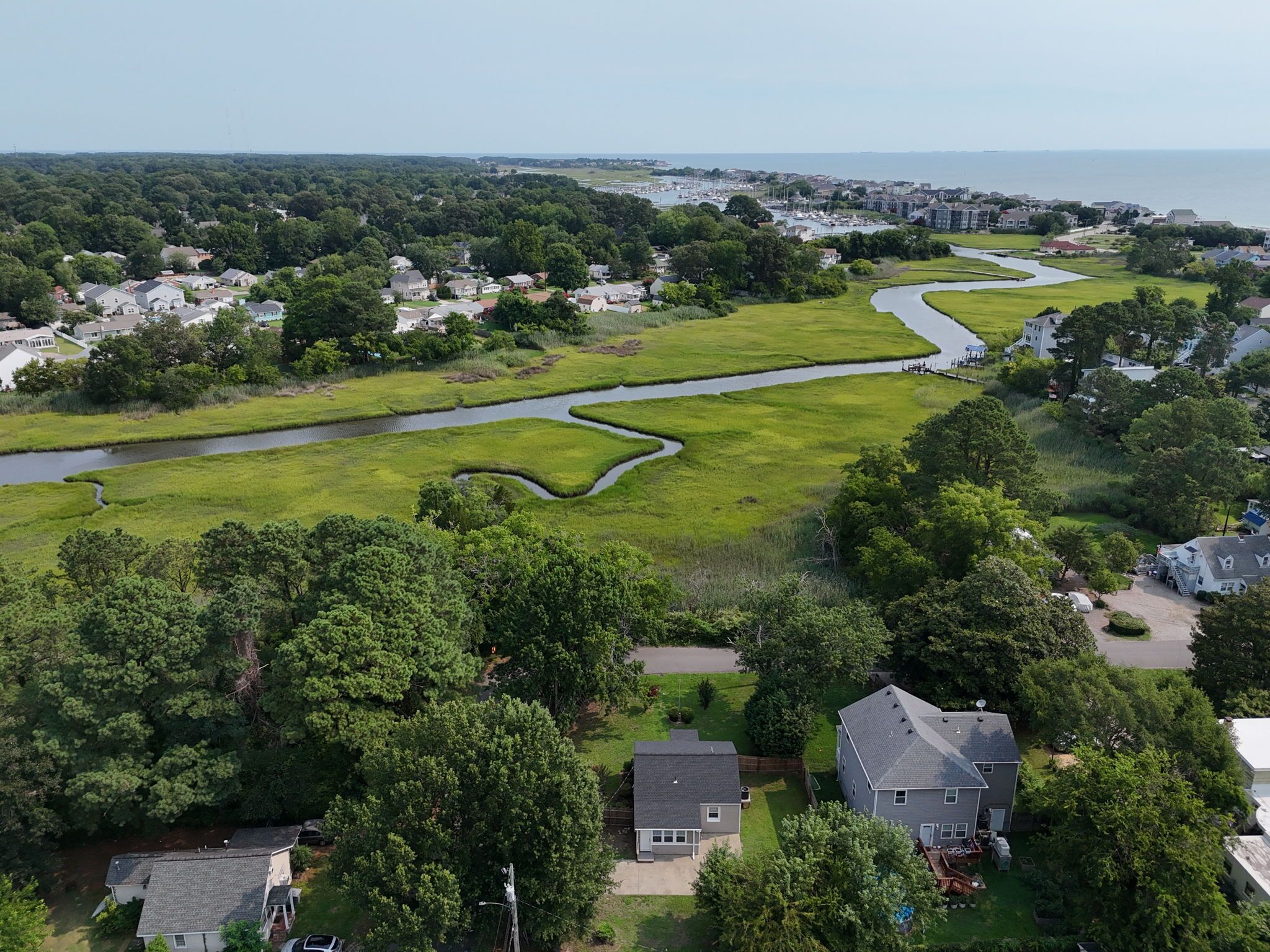 A residential area with houses, a winding river, and a marina in the background.