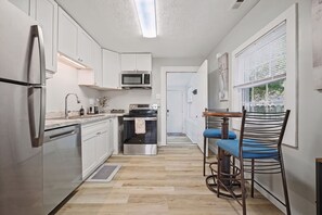 Eine moderne Küche mit Edelstahlgeräten, einer Mikrowelle und einem Essbereich mit Tisch und Stühlen.