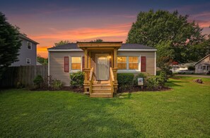 Une maison à deux étages avec un porche à l’avant et une pelouse bien entretenue.