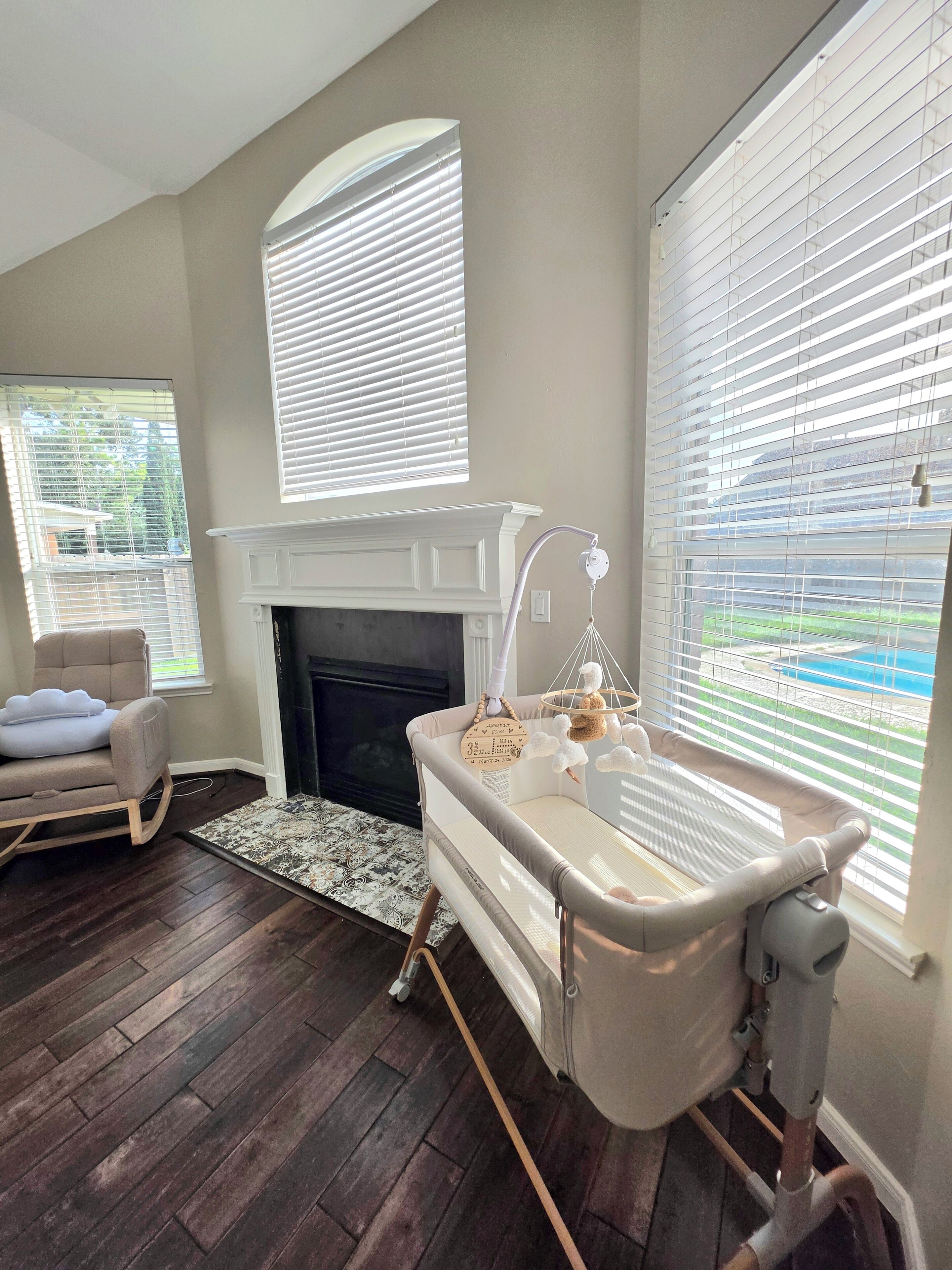 A room with a fireplace, a crib, and a rocking chair.