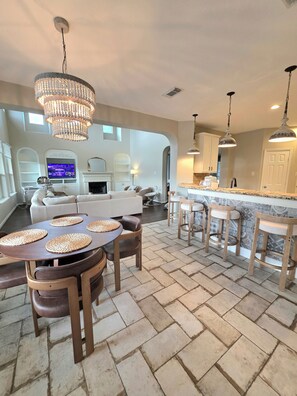 A spacious living area with a fireplace, a television, and a dining area with a round table and chairs. - Grand Conroe Retreat Near The Woodlands, Pool, 2 Primary Suites, Sleeps 8 (Conroe)