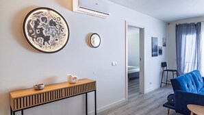 Een moderne woonkamer met een blauwe bank, een houten console en twee decoratieve items aan de muur.