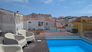 Ein Pool auf dem Dach mit Blick auf Gebäude mit Terrakotta-Dächern.