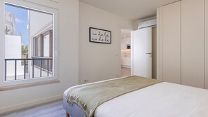 Ein Schlafzimmer mit Bett, einem Balkon, einer Küche und einer Tür zu einem weiteren Raum.