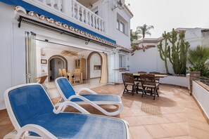 A patio with lounge chairs, a dining table with chairs, and a kitchen area with a view of the street. - La Pomonita - Two Bedroom Apartment, Sleeps 4 (Nerja)
