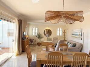 A spacious living area with a dining table, chairs, a sofa, and a large woven ceiling light fixture. - La Pomonita - Two Bedroom Apartment, Sleeps 4 (Nerja)
