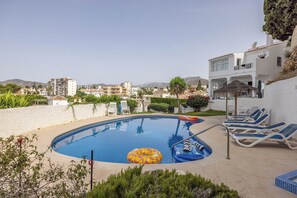 A swimming pool with lounge chairs and inflatable rings, surrounded by a white wall and greenery. - La Pomonita - Two Bedroom Apartment, Sleeps 4 (Nerja)