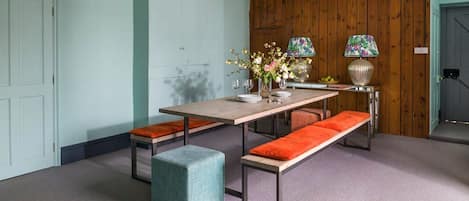 Un coin repas avec une table en bois, des bancs et un vase de fleurs.
