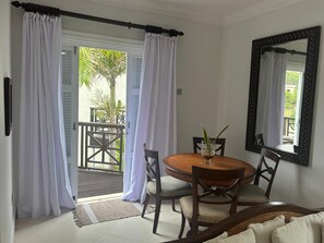 A room with a round wooden table, two chairs, a potted plant, and a large mirror on the wall. - Stylish 2BR Condo at Cap Cove (Gros Islet)