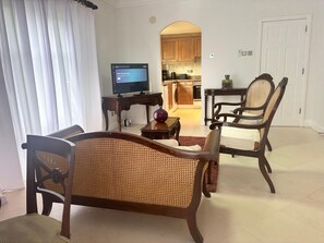 Ein Wohnzimmer mit Sofa, Sessel, Couchtisch und Fernseher.
