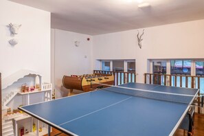 A room with a ping pong table, a foosball table, and a dollhouse.