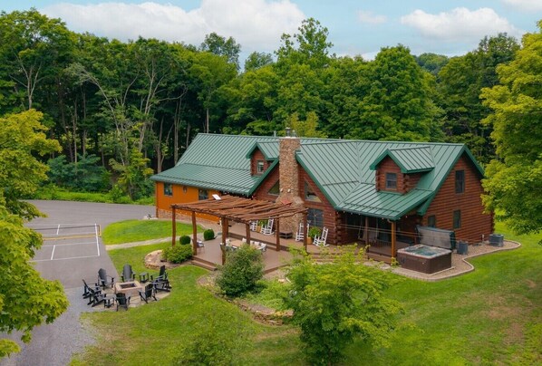 Een lodge met een overdekt terras, buitenmeubels en een hottub.