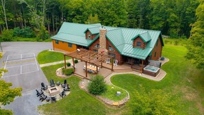 A lodge with a covered patio, outdoor seating, and a hot tub. - Triple Trac Lodge, upscale retreat in the countryside with 7 Bedrooms, hot tub, game room, and so much more. Plenty of fun for everyone! (East Waterford)
