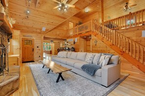A log cabin interior with a sofa, coffee table, and staircase.