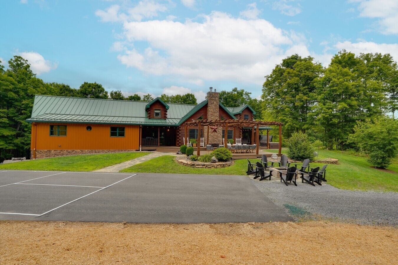 A lodge with a stone facade, a green roof, and a covered patio with outdoor seating.