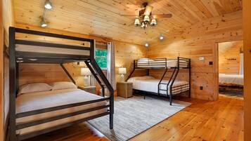 A cabin with two bunk beds, wooden walls, a ceiling fan, and a window.