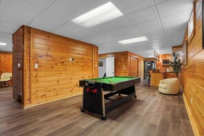 A pool table in a room with wooden walls and a ceiling with recessed lighting.
