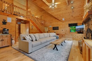 A wooden cabin interior with a sofa, coffee table, and a fireplace. - Triple Trac Lodge, upscale retreat in the countryside with 7 Bedrooms, hot tub, game room, and so much more. Plenty of fun for everyone! (East Waterford)
