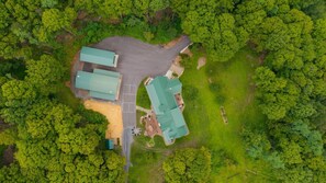 An aerial view of a property with multiple buildings, a parking area, and surrounding greenery.