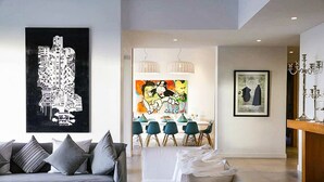 Una sala moderna con un sofá, un comedor con sillas y obras de arte en las paredes.