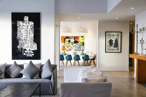 A modern living room with a sofa, a dining area with chairs, and artwork on the walls. - Villa Tallaght - Six Bedroom Villa, Sleeps 12 (Marrakesh)