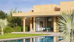Una casa moderna con piscina, un patio cubierto y un comedor con vista a la piscina.