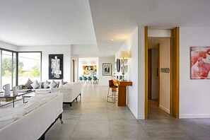 A modern living room with a sofa, a dining area with chairs, and artwork on the walls. - Villa Tallaght - Six Bedroom Villa, Sleeps 12 (Marrakesh)