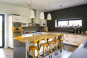 A modern kitchen with a large island, bar stools, and stainless steel appliances. - Villa Tallaght - Six Bedroom Villa, Sleeps 12 (Marrakesh)