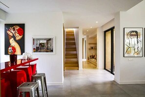 A modern interior with a staircase leading to a second floor, a dining area with red chairs, and artwork on the walls. - Villa Tallaght - Six Bedroom Villa, Sleeps 12 (Marrakesh)