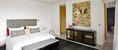 Une chambre moderne avec un grand lit, une console et une œuvre d’art accrochée au mur.