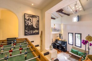 A room with a foosball table, a piano, a sofa, and a painting on the wall. - Maison Huguette - Five Bedroom Villa, Sleeps 10 (Paradou)