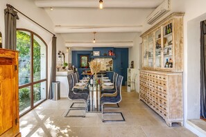 A dining area with a glass table, chairs, and a cabinet with drawers. - Maison Huguette - Five Bedroom Villa, Sleeps 10 (Paradou)