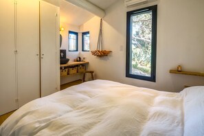 A bedroom with a bed, a window with a view of trees, a bedside table with a lamp, and a wardrobe. - Maison Huguette - Five Bedroom Villa, Sleeps 10 (Paradou)