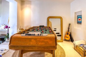 Un tavolo da calcio in una stanza con uno specchio, una chitarra e un quadro appeso al muro.